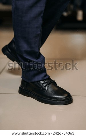 The image shows a person wearing black boots while standing indoors.