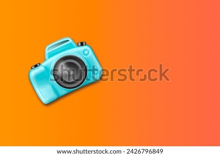 Blue plastic camera on orang gradient background. Copy space.Travel concept. Travel background.