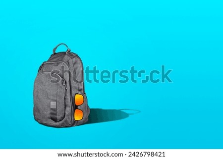 Backpack with sunglasses on a blue background. Copy space. Travel concept. Travel background.