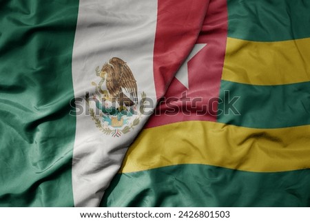 big waving national colorful flag of togo and national flag of mexico . macro