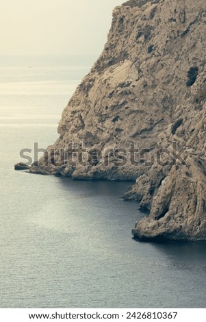 Cliff by the sea. Rocky wall of a mountain facing the sea. Royalty-Free Stock Photo #2426810367