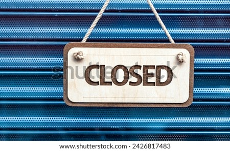 Shop Closed sign hanging in front of a metal shutter