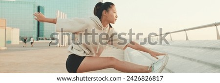 Asian girl in sportswear does workout, stretching and gymnastics on modern buildings background, Panorama