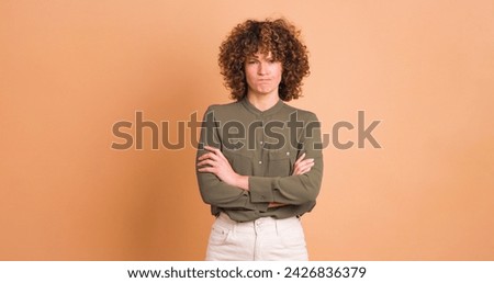 Disagreeing young woman with twisted mouth on beige background Royalty-Free Stock Photo #2426836379