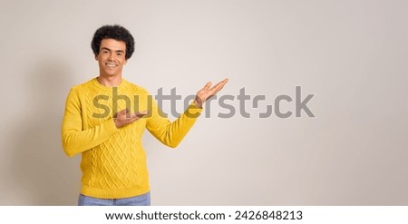 Portrait of young smiling businessman advertising new product on copy space over white background