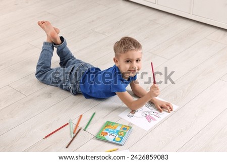 Cute little boy coloring on warm floor at home. Heating system