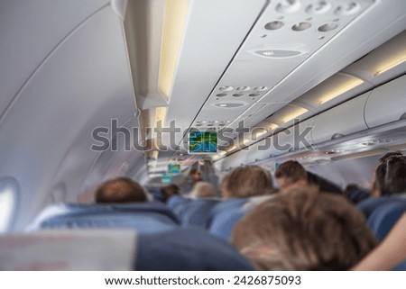 Rear view of the interior of the plane filled with tourists sittingon the seats. The photo contains no recognizable faces.