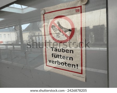 sign "Feeding pigeons prohibited" behind a glass pane