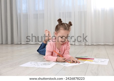 Cute little girl coloring on warm floor at home. Heating system
