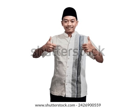 Happy smiling handsome young Asian Muslim man showing thumbs up gesture at the camera with a satisfied expression isolated over white background.
Ramadan and Eid al fitr concept