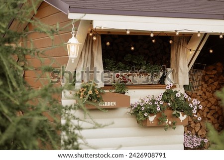 Cozy window, adorned with flowers, illuminated by string lights. Wooden GARDEN sign adds rustic touch. Concept: home decor, gardening inspiration.