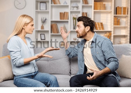 Emotional support for abused families depicted: An enraged husband raises his hand against his wife on their couch, poised to strike Royalty-Free Stock Photo #2426914929