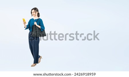 Full body photo of a white woman walking while looking at her smartphone