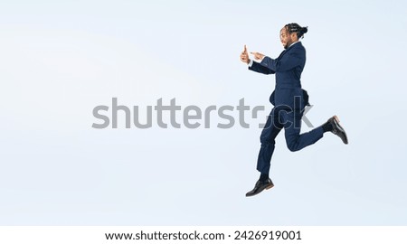 Full body photo of a black businessman jumping while looking at his smartphone