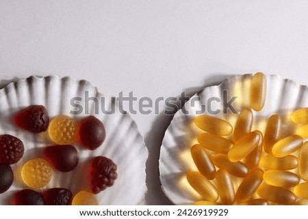 chewable supplements, nutritional gummies, edible health concept. colorful marmalades and omega 3 vitamins on shell on white background. copy space  Royalty-Free Stock Photo #2426919929