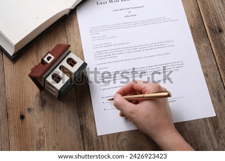 Woman signing Last Will and Testament at wooden table, above view
