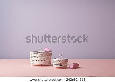A accessory storage case against light pink and light purple background. With a pink rose flower leaf. An empty platform for display cosmetic products, food and props.