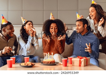 Diverse group of friends enjoying birthday party with cake and laughter, sharing moments of happiness celebrating together in modern living room at home. Bday celebration concept