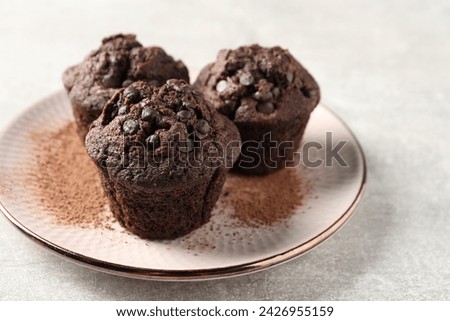 Delicious chocolate muffins and cacao powder on light grey table, closeup. Space for text Royalty-Free Stock Photo #2426955159