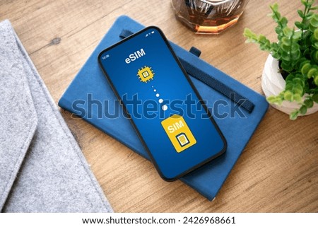 phone with Sim card replacement on eSim screen background of wooden table in office  