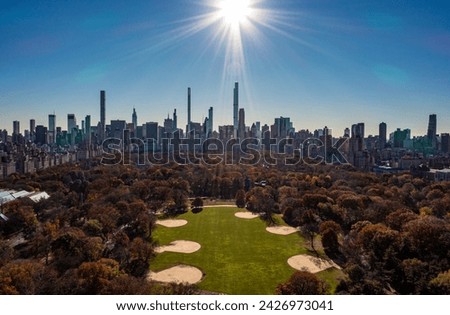 Wide panoramic aerial shot of autumn in Central Park and surrounding high rise buildings against sunshine. Manhattan, New York City, USA