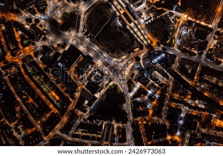 Birds eye view of tall financial and commercial buildings with shadow and cars moving on city street during night with illuminated lights in London city Royalty-Free Stock Photo #2426973063