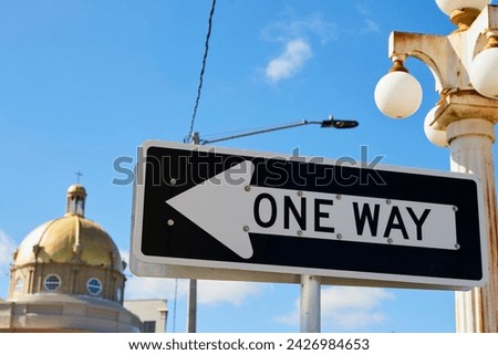 Traffic sign with the words One Way, in the background is the dome of a church.