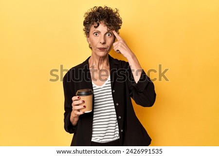 Businesswoman holding takeaway coffee on yellow showing a disappointment gesture with forefinger.