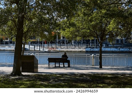 Man sitting on a bench in silhouette in the city of Tampa.