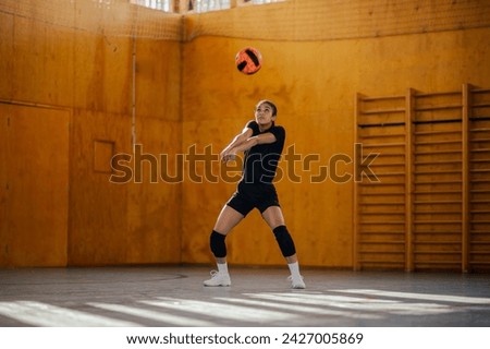 A multicultural female teenage volleyball player is hitting and passing the ball on indoor court during the training. An active sportswoman in action passing the ball on volleyball court on training. Royalty-Free Stock Photo #2427005869