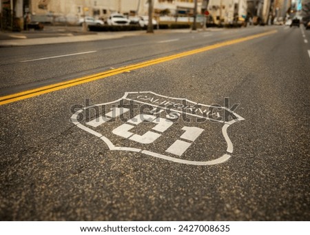 Highway 101 sign painted on the black asphalt road with city diffused in the background. The shot is from Oceanside California Royalty-Free Stock Photo #2427008635