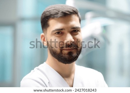Close-up portrait of a smiling dentist in the office of a modern dental clinic. The doctor orthodontist is at work. Handsome beard young man looking at camera Royalty-Free Stock Photo #2427018243