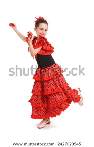 A little girl in a red Spanish dress dances flamenco. White background