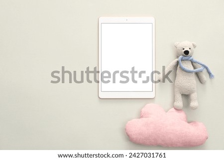 Modern tablet, toy cloud and bear on light background, flat lay. Space for text