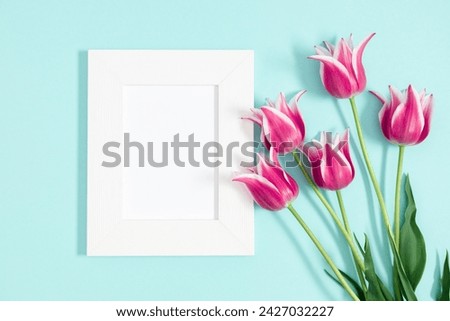 Beautiful composition spring flowers. Photo frame, bouquet of pink tulips flowers on pastel blue background. Valentine's Day, Easter, Birthday, Happy Women's Day, Mother's Day. Flat lay, top view