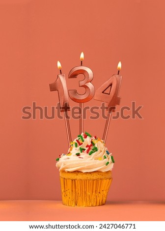 Birthday cupcake with candle number 134 - Coral fusion background