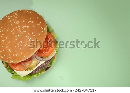 Burger with delicious patty on green background, top view. Space for text