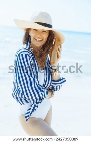 smiling stylish 40 years old woman on the ocean shore with sunscreen.