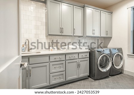 Interior of bathroom powder room with grey walls wooden cabinets white granite marble countertops white sink laundry room with appliances and decoration Royalty-Free Stock Photo #2427053539