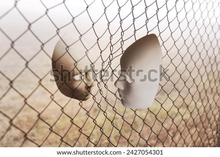 surreal face to face between two masks divided by a metallic net, abstract concept