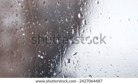 Macro of water drops on glass. Large rain drops strike window during winter shower. Pure rain drops. Royalty-Free Stock Photo #2427064487