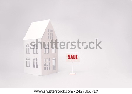 Paper cut house and house for sale sign. Minimal concept for the real estate market. Selective focus, copy space