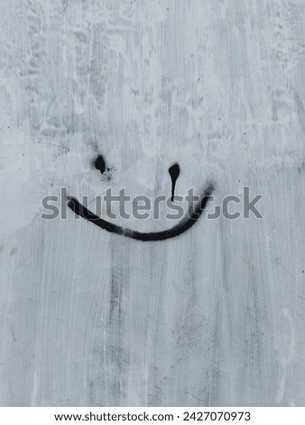 A picture or graffiti in the form of a smiley emoji on a white wall.