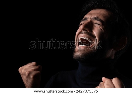 Stressed Young angry man screaming and shouting Frustrated handsome man agonizing and torturing expression He get maddening and overwhelming rage in the dark room black background Agressive man	