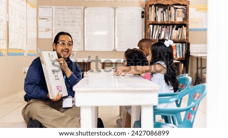 Hispanic adult male teacher holding a book and teach a preschool children. Royalty-Free Stock Photo #2427086899