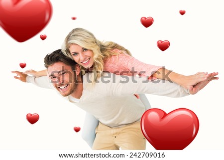 Handsome man giving piggy back to his girlfriend against hearts