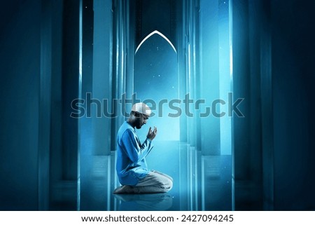 Young asian muslim man with beard praying in the mosque door arch at beautiful blue night sky with stars