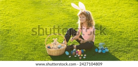 Child boy with easter eggs and bunny ears outdoor. Cute kid having happy easter in park. Cute little boy, easter bunny children spring outdoor. Wide photo banner for website header design.