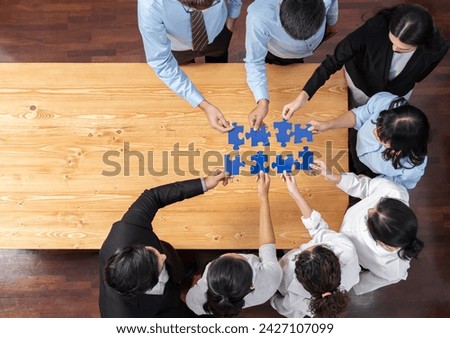 Multiethnic business people holding jigsaw pieces and merge them together as effective solution solving teamwork, shared vision and common goal combining diverse talent. Panorama top view. Meticulous Royalty-Free Stock Photo #2427107099