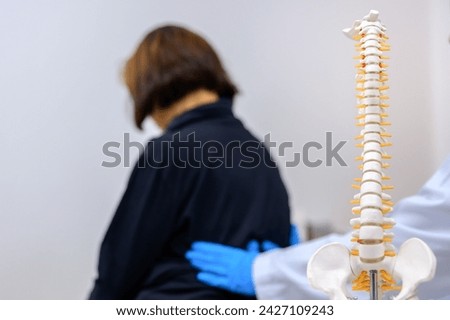 Spinal Focus Picture An orthopedic surgeon or therapist is showing a spinal model and explaining to a female patient her spinal problems. Health care concept and aging and back pain